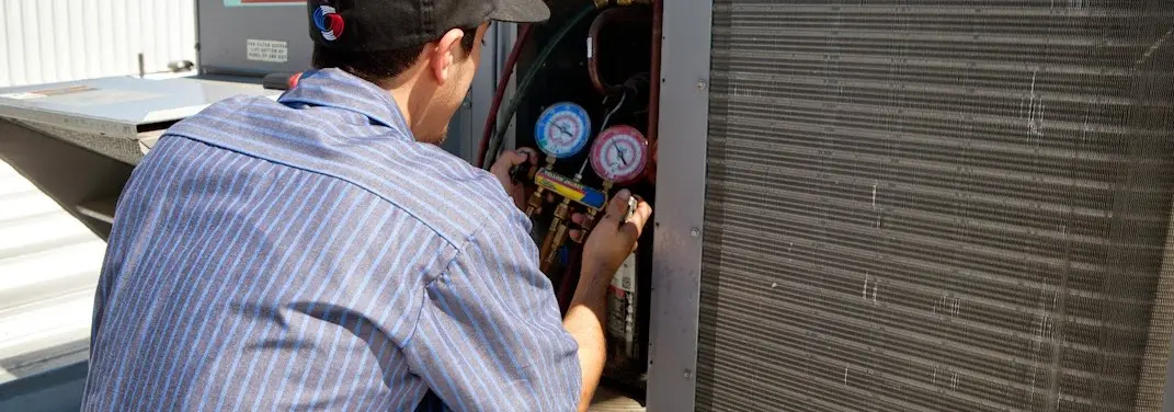 HVAC technician servicing a condenser unit in St. Clair